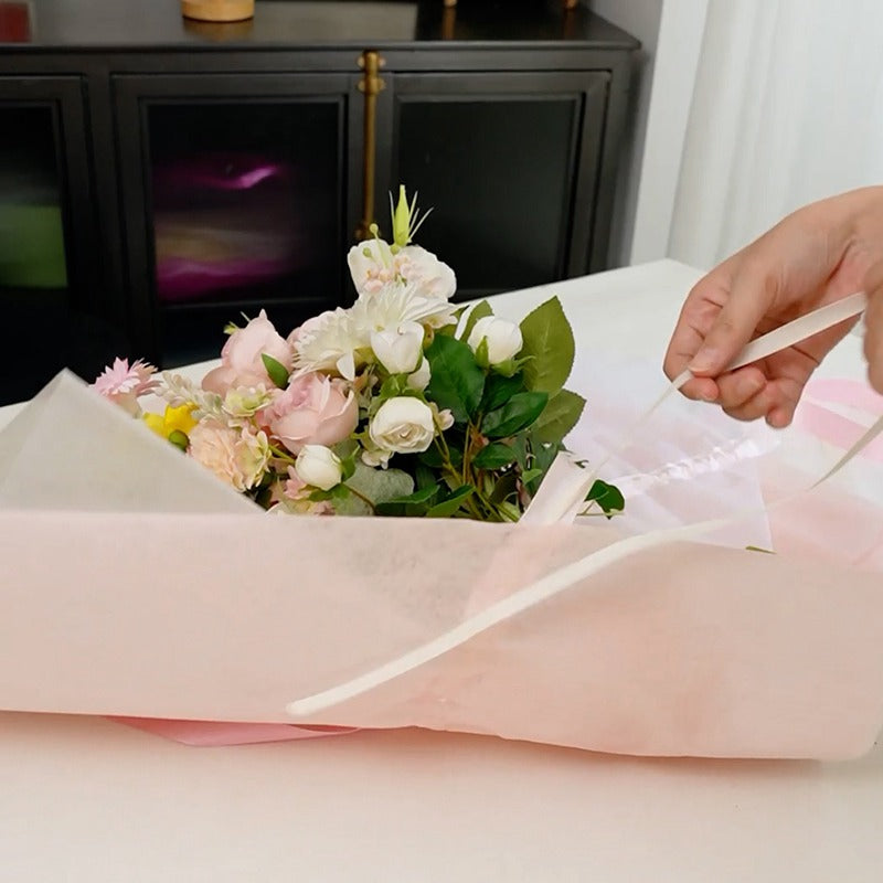 Ejemplo de uso de papel coreano Supreme con listón integrado, listo para usar. Colores beige, amarillo, rosa, lila y celeste para envolver ramos de flores. Materiales para florerías.