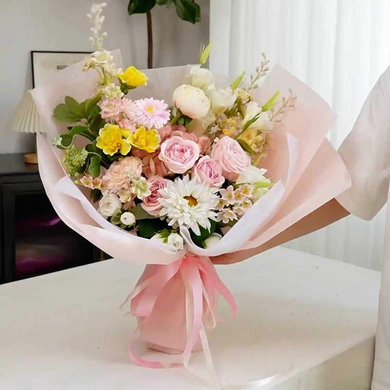 Ejemplo de uso de papel coreano Supreme con listón integrado, listo para usar. Colores beige, amarillo, rosa, lila y celeste para envolver ramos de flores. Materiales para florerías.